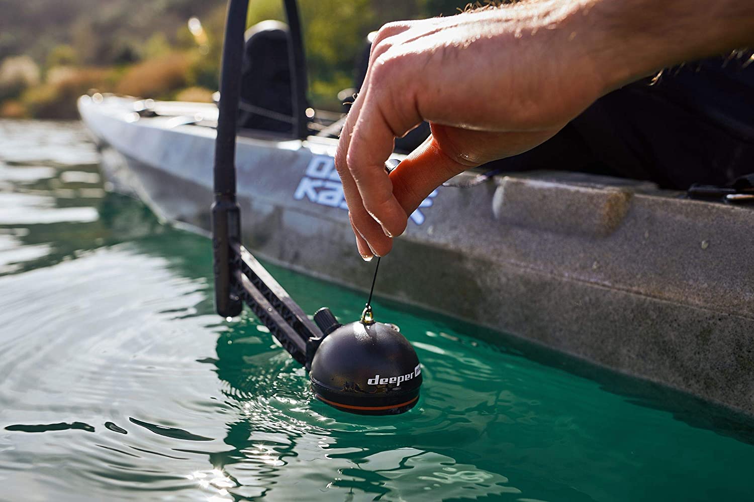 Castable sonar being lowered beside a fishing kayak
